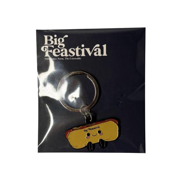 A Hotdog Keyring by 2025 featuring a cute smiling hotdog charm, packaged on a Big Feastival card with an unopened dark background.